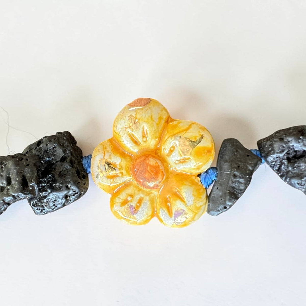 Close-up of hand-painted Caltagirone ceramic flower and natural Etna lava stone beads on handmade Sicilian necklace