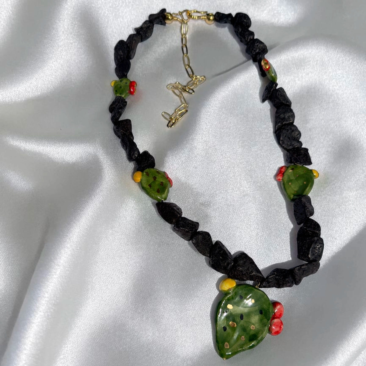 Full view of handmade Sicilian prickly pear necklace with Mount Etna lava stone, Caltagirone ceramic pendant and gold-tone extension chain