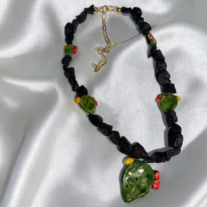 Full view of handmade Sicilian prickly pear necklace with Mount Etna lava stone, Caltagirone ceramic pendant and gold-tone extension chain