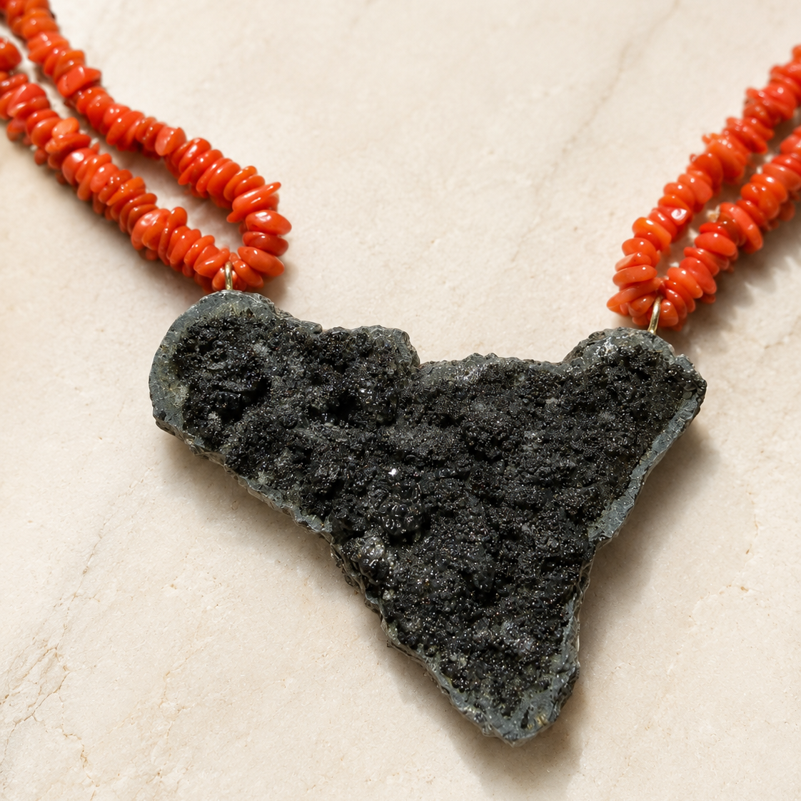 Close-up of Sicily-shaped Mount Etna lava stone pendant with Mediterranean red coral necklace