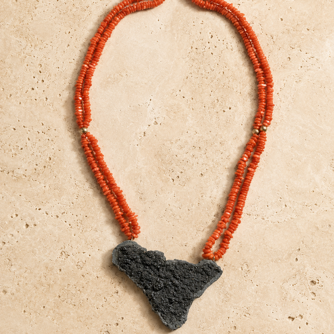 Handmade Sicilian red coral necklace laid flat with Sicily-shaped Mount Etna lava stone pendant