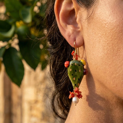 Woman wearing a handmade Sicilian prickly pear earring in hand-painted Caltagirone ceramic with red coral and freshwater pearl