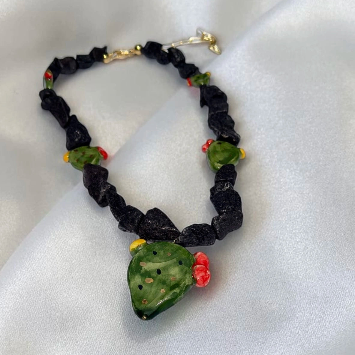 Close-up of handmade Sicilian prickly pear necklace with Mount Etna lava stone and hand-painted Caltagirone ceramic pendant