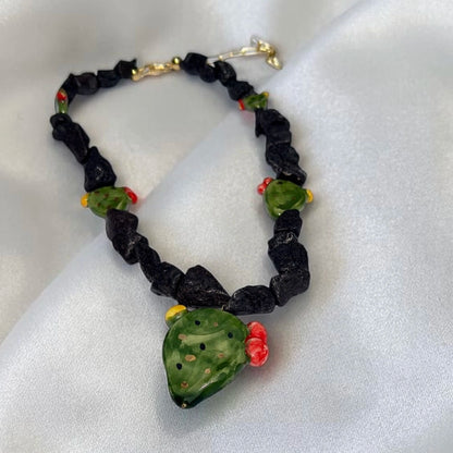 Close-up of handmade Sicilian prickly pear necklace with Mount Etna lava stone and hand-painted Caltagirone ceramic pendant