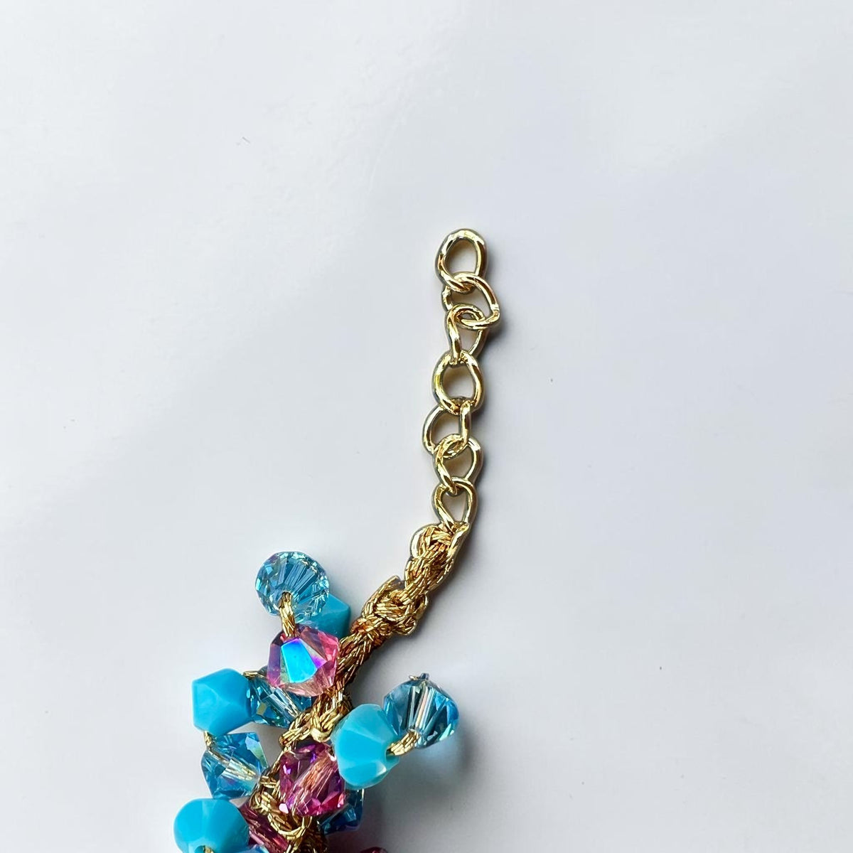 Close-up of gold-tone extension chain, crochet braid and turquoise Swarovski crystals on a handmade Sicilian bracelet