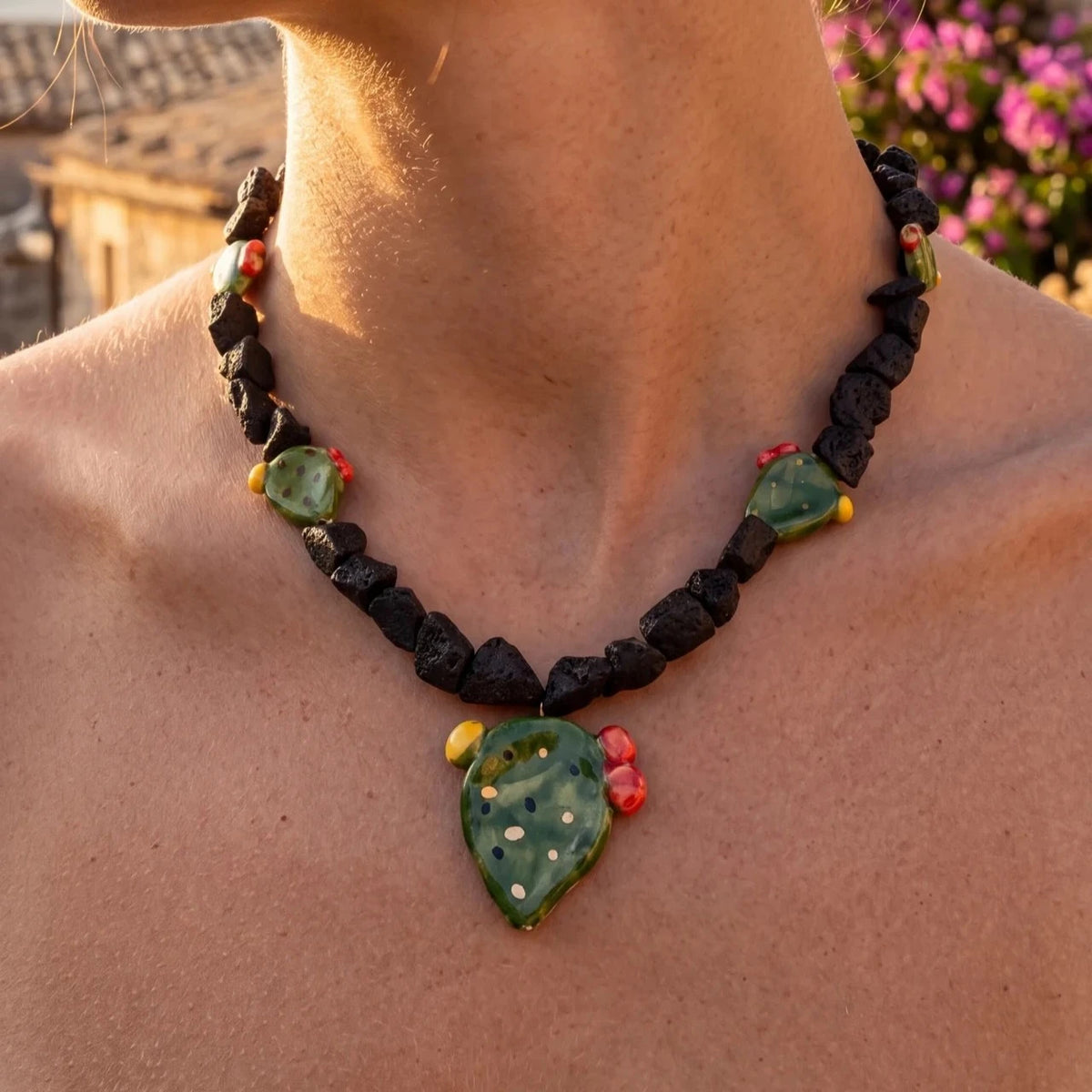 Woman wearing a handmade Sicilian necklace with Mount Etna lava stone and hand-painted Caltagirone ceramic prickly pear pendant