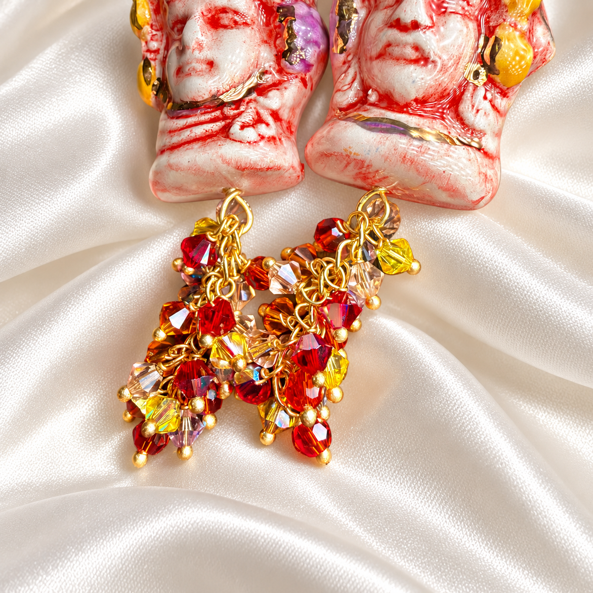 Close-up of hand-painted Caltagirone ceramic Moor’s Head earrings with 10% gold lustre, multicolored Swarovski crystals and gold-plated brass chains.