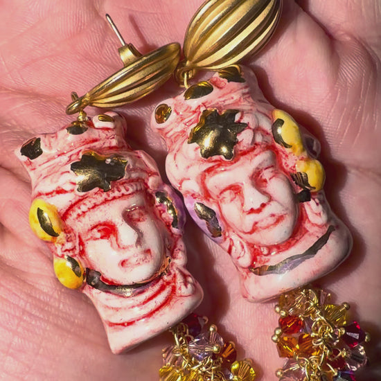 Close-up video of hand-painted Caltagirone ceramic Moor’s Head earrings in red and white with 10% gold lustre, Swarovski crystals and gold-tone details.