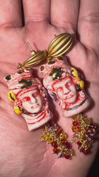 Close-up video of hand-painted Caltagirone ceramic Moor’s Head earrings in red and white with 10% gold lustre, Swarovski crystals and gold-tone details.
